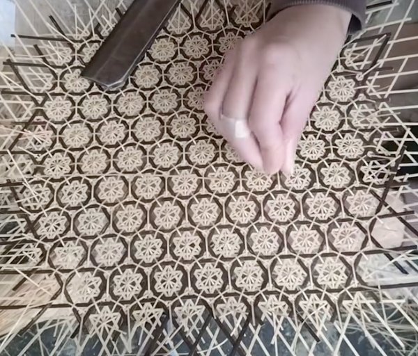 菊模様の編み込みに竹ひごを通す職人の手